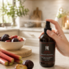 AromaHoliday Glow Rhubarb & Black Plum room spray in a bright kitchen setting with fresh rhubarb and plums, inspired by Yorkshire fragrance notes.