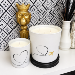 Luxury white scented candles by AromaHoliday featuring elegant minimalist heart and airplane designs with gold detailing, stylish modern home décor and premium travel-inspired fragrance styling.