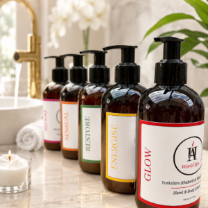 AromaHoliday World Spa luxury hand and body lotion collection displayed in a premium spa bathroom setting featuring Glow, Energise, Restore, Sensual and Bloom fragrances in recyclable amber bottles beside a gold tap and candle.