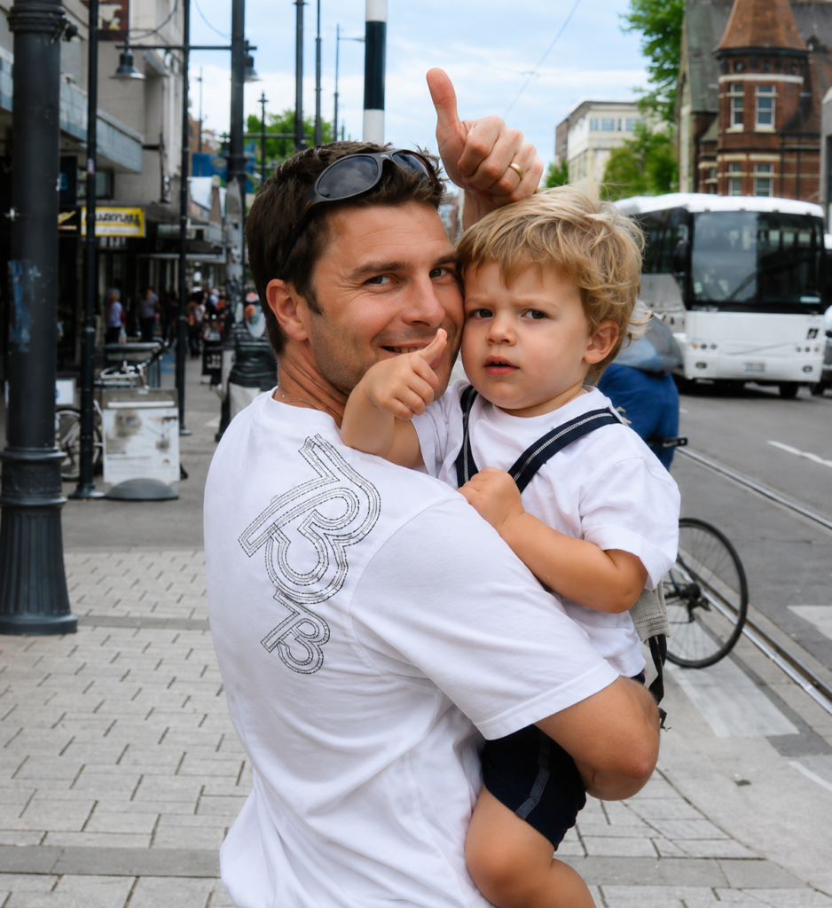 Young Mark Jordan holding his young son Max during their world travels — a special memory that inspired the AromaHoliday journey. Captured in a vibrant city setting, this image represents travel, family, adventure, and the emotional connection between scent and memory.
